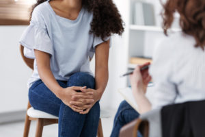 A woman sits across from a therapist while they take notes on a clipboard. This could represent depression treatment in Grand Rapids, MI, and the support a depression therapist in Kent County, MI can offer. Learn more about how online depression therapy in Kent County, MI can support you from home.