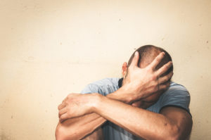 A man covers his face as he sits against a wall. This could represent the pain of trauma a trauma therapist in Grand Rapids, MI can address. Learn more about trauma therapy in Grand Rapids, MI and other services. 49525 | 49506 | 49534