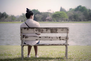 A woman sits alone on a bench, looking at the empty spot next to her. Learn more about how grief counseling in Grand Rapids, MI can offer support by contacting a grief counselor in Grand Rapids, MI. We offer online grief counseling in Kent County, MI and more. 