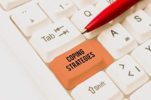 Photo of a keyboard with an orange key labeled "Coping Strategies". Representing that the help you need with trauma therapy in MI in one click away! Reach out now for help.